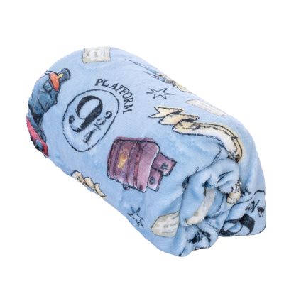 Světlomodrá deka s motivy Harry Potter, včetně „Platform 9 3/4“, kufru a lahviček s lektvary.