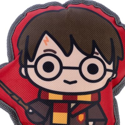 Jucărie cu motiv Harry Potter, fundal roșu, eșarfă galben-roșie și baghetă vizibile.