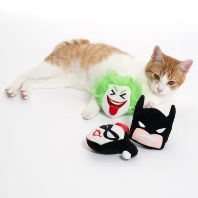 Kolme kissanlelua sarjakuvateemalla: Joker, Harley Quinn ja Batman. Punavalkoinen kissa makaa vieressä.