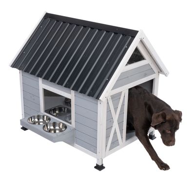 Niche pour chien en bois avec toit en métal, deux gamelles en acier inoxydable intégrées à l’avant, chien marron sortant de la niche.