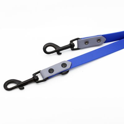 Blått hundkoppel med gråa läderdetaljer och svarta metallkarbiner i båda ändar.