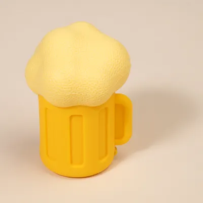 Giocattolo per cani giallo a forma di boccale di birra con schiuma, realizzato in materiale morbido.