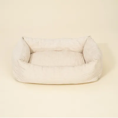 Letto rettangolare, beige chiaro imbottito con lati rialzati in tessuto.