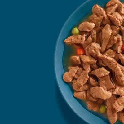 Tray with meat pieces in gravy, with visible peas and carrot pieces. Tray with meat pieces in gravy, with visible peas and carrot pieces.
