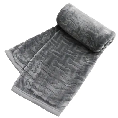Coperta grigia con motivo a ossa, materiale morbido, arrotolata e parzialmente aperta.