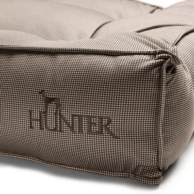 Vue détaillée d’un coussin pour chien marron à motif pied-de-poule avec logo brodé « Hunter » et silhouette de chien.