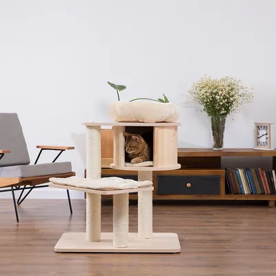 Wooden cat tree with three levels: cave, lounging area and padded top platform. Cat sitting in the cave. Modern living room in the background.