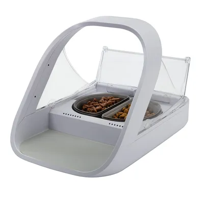 Distributeur automatique blanc avec deux gamelles, l’une contenant de la pâtée et l’autre des croquettes. Structure en plastique avec couvercles transparents relevés.