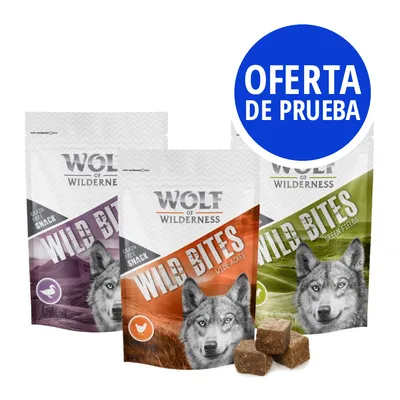 Wolf of Wilderness Wild Bites, snack sin cereales para perros en tres variedades. Texto visible: OFERTA DE PRUEBA. Cubos de snack delante de los envases.