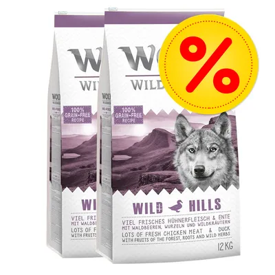 2 sacchi di crocchette Wild Hills 12 kg, ricetta senza cereali, pollo e anatra, con frutti di bosco, radici ed erbe selvatiche. Etichetta promozionale con simbolo percentuale.