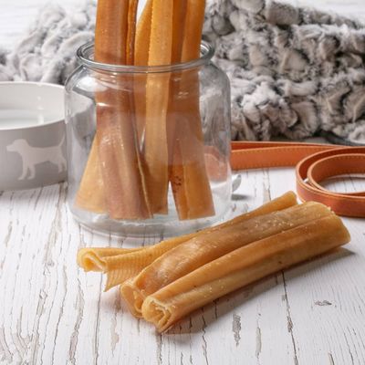 Several natural chew sticks displayed in a glass jar and on a wooden surface, shown for size and texture reference.