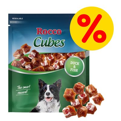 Confezione di snack per cani Rocco Cubes, visibili cubetti e scritta 'Duck & Fish'. Simbolo percentuale giallo con rosso indica offerta o promozione.
