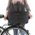 Schwarze Fahrrad-Transportbox mit Netzabdeckung, befestigt am Gepäckträger eines Fahrrads. Person hält die Box an den Seitengriffen.