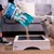 Sanicat Clumping cat litter poured into a wooden litter box, with a grey cat standing next to it. Packaging displays brand name and product details.