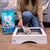 Sanicat Clumping cat litter with Oxygen Control, woman demonstrating use with scoop in wooden litter box. Packaging visible: 10L, antibacterial, dust-free.