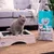 Sanicat Clumping White stelivo pre mačky, 10 l, s Oxygen Odor Control a vôňou Cotton Fresh. Mačka stojí na drevenej mačacej toalete vedľa balenia.