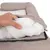 Main ouvrant la housse zippée d’un coussin pour animal, montrant le rembourrage en tissu blanc à l’intérieur du lit beige.