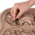 Hand places treat in brown intelligence toy with various recesses and obstacles.