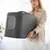 Closed, portable cat litter box in dark grey with transparent entrance and carrying handle.
