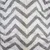 Close-up of white fabric with grey zigzag pattern and yellow stripes. Material texture visible.