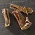 Trois morceaux de friandises séchées pour chien, aspect naturel et rugueux, posés sur une surface noire. Aucun emballage ou marque visible.