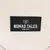 Nomad Tales München. Schwarzes Label mit weissem Schriftzug auf beigem Hintergrund.