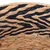 Geflochtenes Material aus Naturfasern mit schwarzen Zierstreifen, Detailansicht.