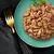 Chunks of wet pet food in gravy served on a green plate, garnished with a sprig of parsley.