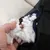 Close-up of a hand removing filling material from an opened black fabric cover. Visible are white and beige foam pieces and fibres.