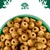 Close-up of round, hole-centred dry pet food pieces in a green bowl, shown under a tree and animal emblem.