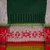 Nahaufnahme eines gestrickten Materials mit grünem, rotem und weissem Muster, einschliesslich Schneeflocken-Designs.