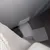 Gros plan sur une fermeture à scratch en tissu gris, cousue sur un article textile. Étiquette blanche visible en arrière-plan.