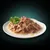 Chunks of meat in gravy served on a white plate with a garnish of parsley, showing the texture and appearance of the wet food product.