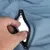 Gros plan sur une main ouvrant une poche zippée en tissu bleu, doublure blanche visible à l’intérieur. Fermeture éclair noire.