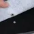 Gros plan sur un bouton-pression en métal reliant deux couches de tissu, une blanche et une noire, avec une main soulevant la couche supérieure.