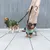 Deux chiens en manteaux pour chien, l’un vert foncé et l’autre vert clair, tenus en laisse par une personne en manteau beige, debout sur un trottoir urbain.