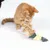 Chat roux jouant avec un jouet en forme de poisson composé de tissu, plumes et bandes jaunes. Partie d’un autre chat visible à gauche.