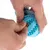Una mano muestra cómo se introduce una golosina en una pelota de juego azul con protuberancias.