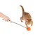 Caña de juego con bola de peluche naranja, gato jugando con ella. Demostración del uso del juguete.
