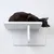 Gatto nero sdraiato su una piattaforma da parete bianca dal design minimalista.
