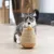 Juguete para gatos de madera y cuerda con bola colgante, mostrado por un gato.