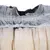 Gros plan sur la texture et les couches d’un matériau absorbant en tissu non tissé, avec élastique visible. Couleurs : beige et gris.