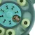 Jeu d’intelligence vert pour chien avec compartiments ronds et os, friandises en forme d’os visibles dans les cases ouvertes.