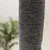 Gros plan sur un poteau recouvert de tissu gris, texture tissée visible. Aucun logo ni texte apparent.