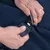 Close-up van een hand die een metalen clip aan een blauwe stof bevestigt. Toont het gebruik van een gordelsysteem met clip sluiting.