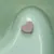 Heart-shaped tablet in pink colour on a green surface.