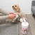 Person reinigt die Pfote eines Hundes mit TIKI Pet Care Wipes aus einer weissen Dose mit rosa Etikett und Hundemotiv.