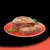 Sliced block of wet pet food with visible herbs on a red plate, shown in cross-section to display texture. No brand or text visible.