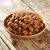Croquettes rondes marron dans un bol en bois, présentées sur une table en bois. Aucun emballage ni marque visible.