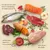 Ingredientes visíveis: peixe inteiro, salmão, carne de vaca, fígado, peito de frango, ovo, batata-doce, maçã, espinafre, ervas. Texto: 'Elevado teor de carne, peixe e ingredientes de origem animal', 'Valiosa fruta, legumes e ervas aromáticas', 'Sem adição de cereais'.
